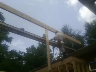 Carpenter setting a ridge beam over a new addition frame — Ice Dam Removal by Roofing Brothers in Harlem