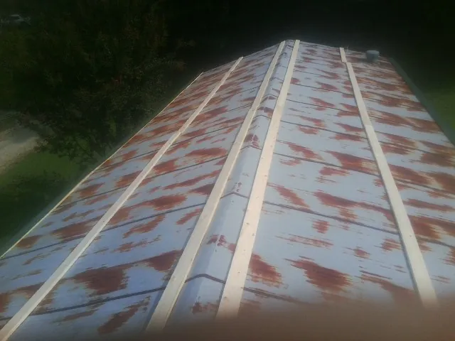 Rusted metal roof panels with new wood purlins before replacement — Storm Damage Roof Repair in Harlem by Roofing Brothers