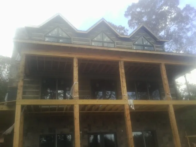Dormers and porch framing on a large log home under construction — Roof Coating work by our crew in Harlem