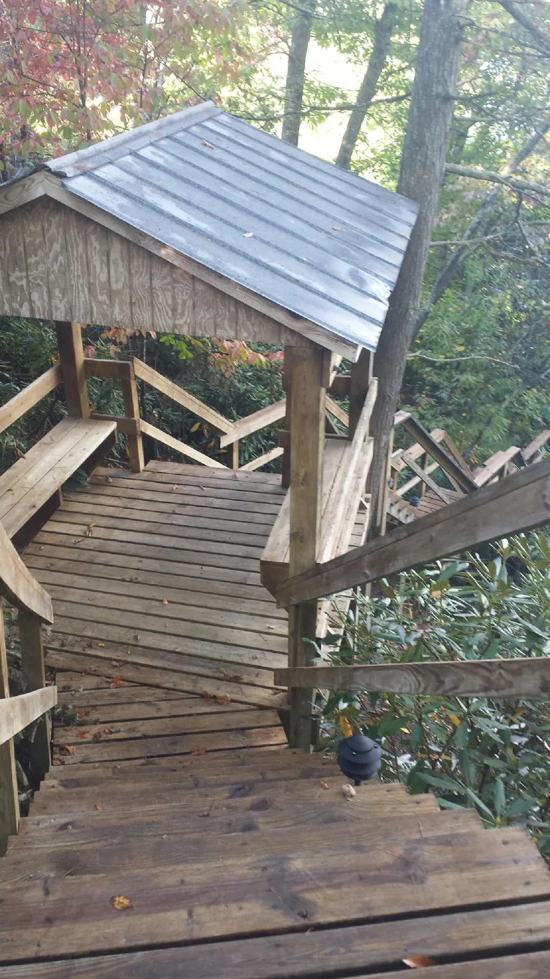 Metal roofed shelter over wooden steps on a wooded walkway — Skylight Repair & Installation work by our crew in Harlem