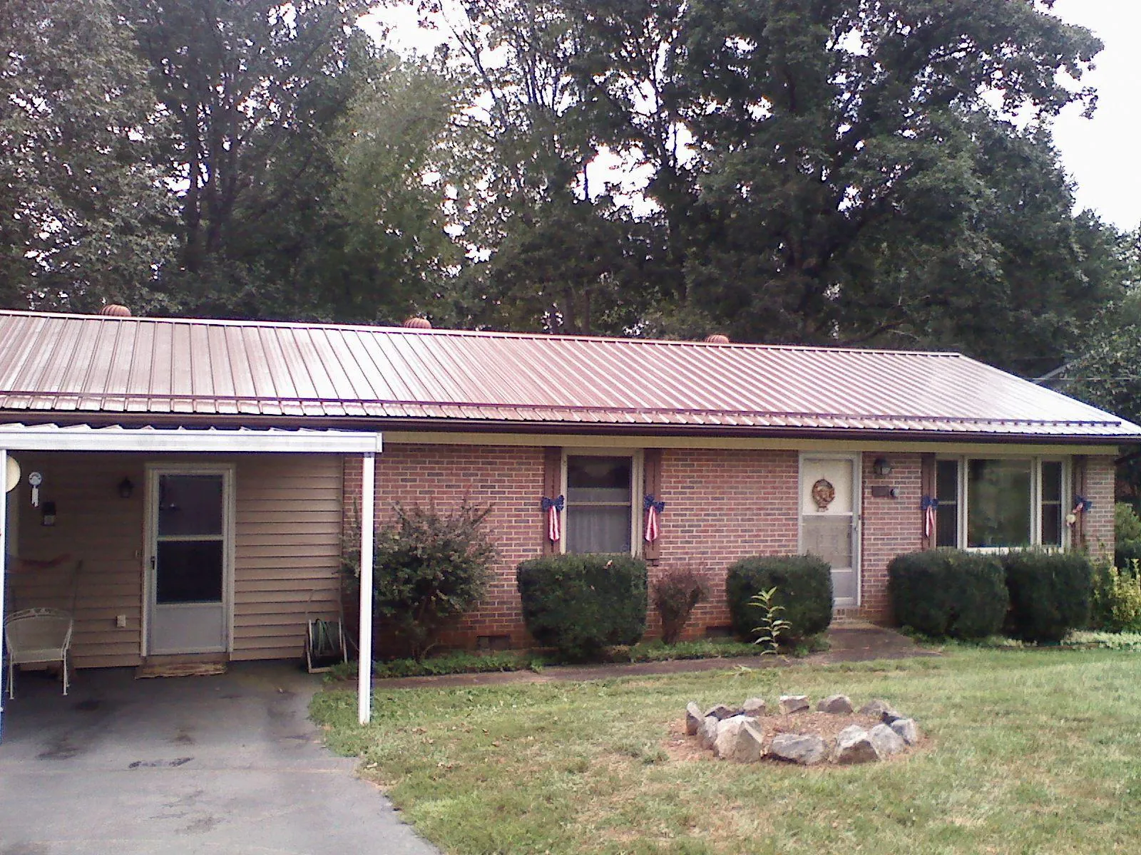 Bronze metal roof and carport on a brick ranch home — Roof Repair work by our crew in Harlem