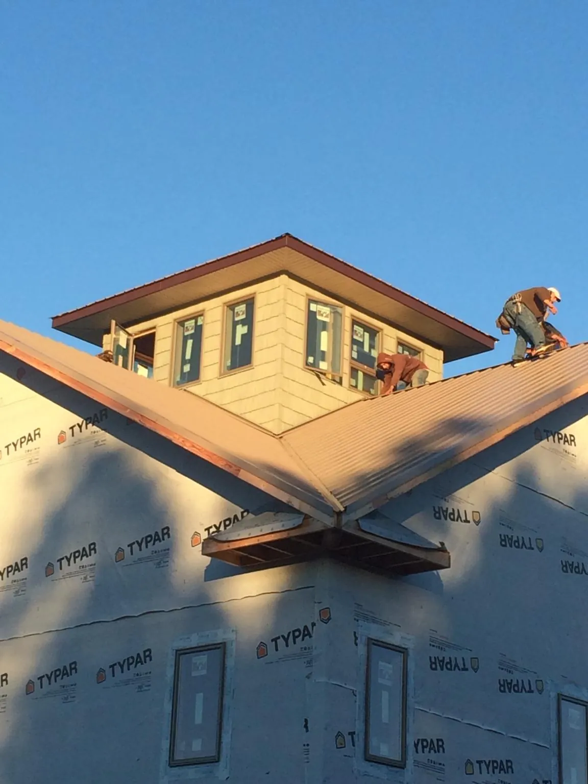 Roofers working around a rooftop cupola on a new metal roof at sunset — Roof Waterproofing in Harlem by Roofing Brothers